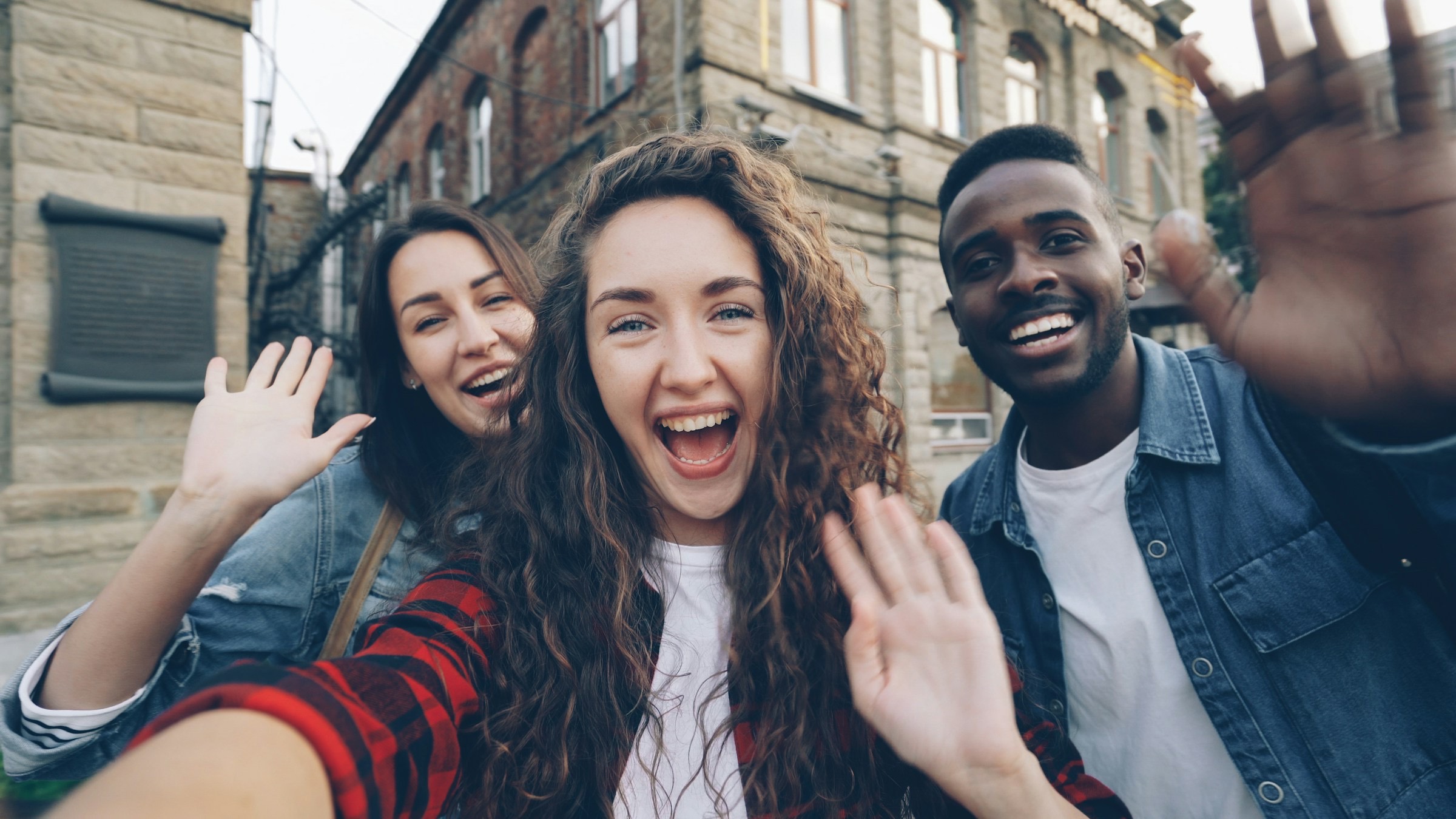 Prieteni studenți care salută veseli pe o stradă din oraș